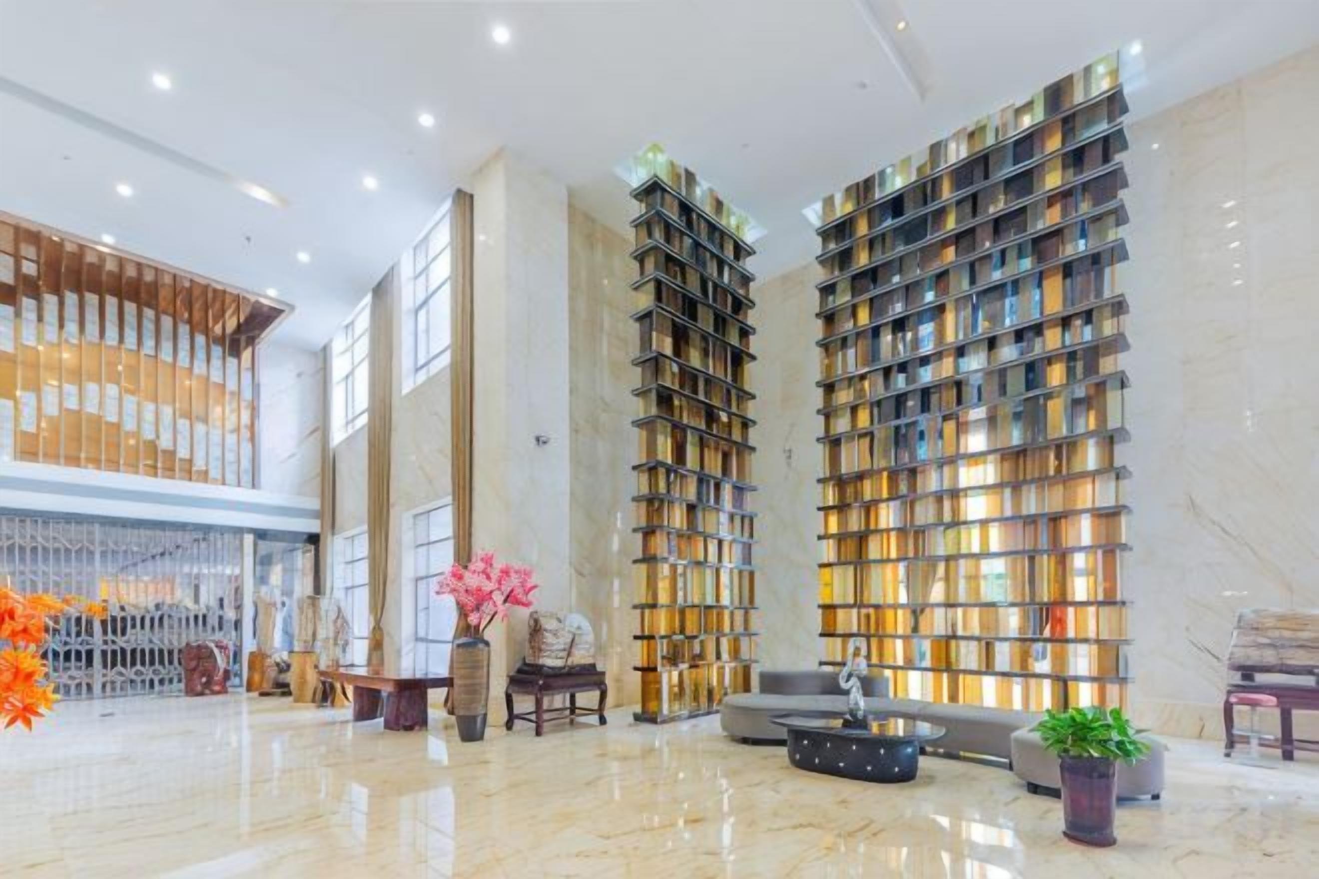 Un hall d’entrée spacieux avec un plafond haut, une grande bibliothèque et un coin salon.