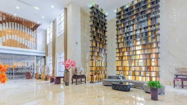 Eine geräumige Lobby mit hoher Decke, Marmorboden und einer großen Bücherwand.