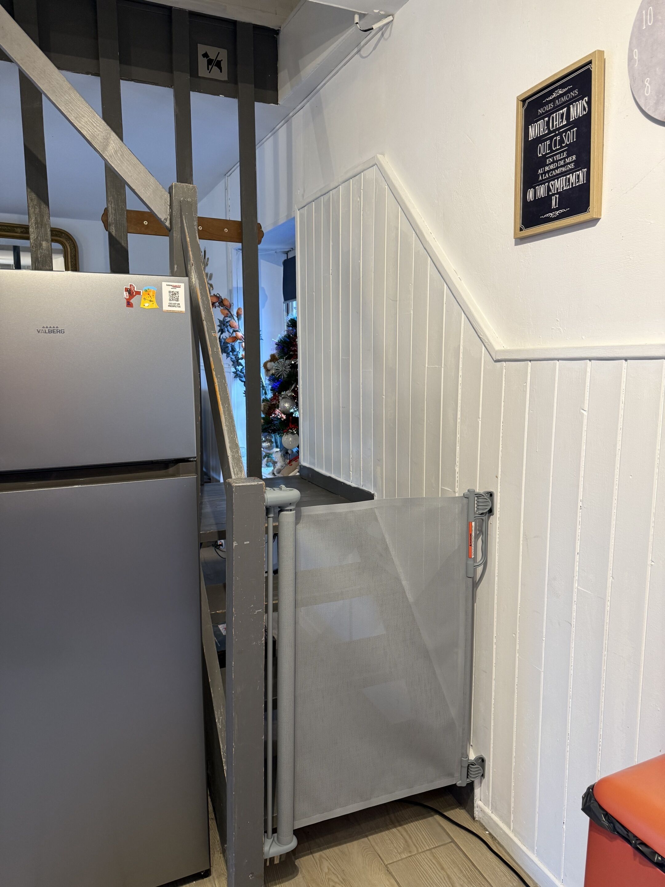 A kitchen with a refrigerator, a metal gate, and a sign on the wall.