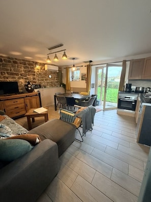 A spacious living area with a sofa, a dining table, and a kitchen area with a stove and cabinets.