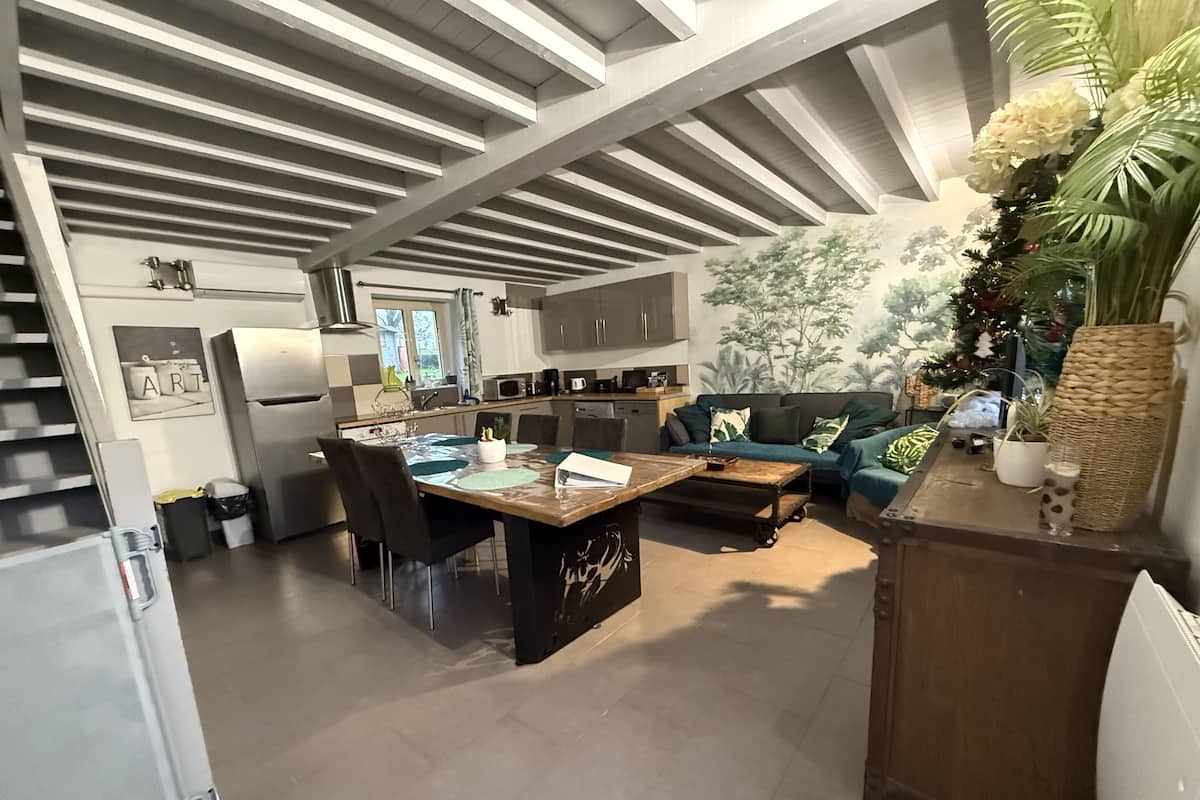 Eine moderne Küche mit Kochinsel, Essbereich mit Stühlen und Wohnbereich mit Sofa und Couchtisch.