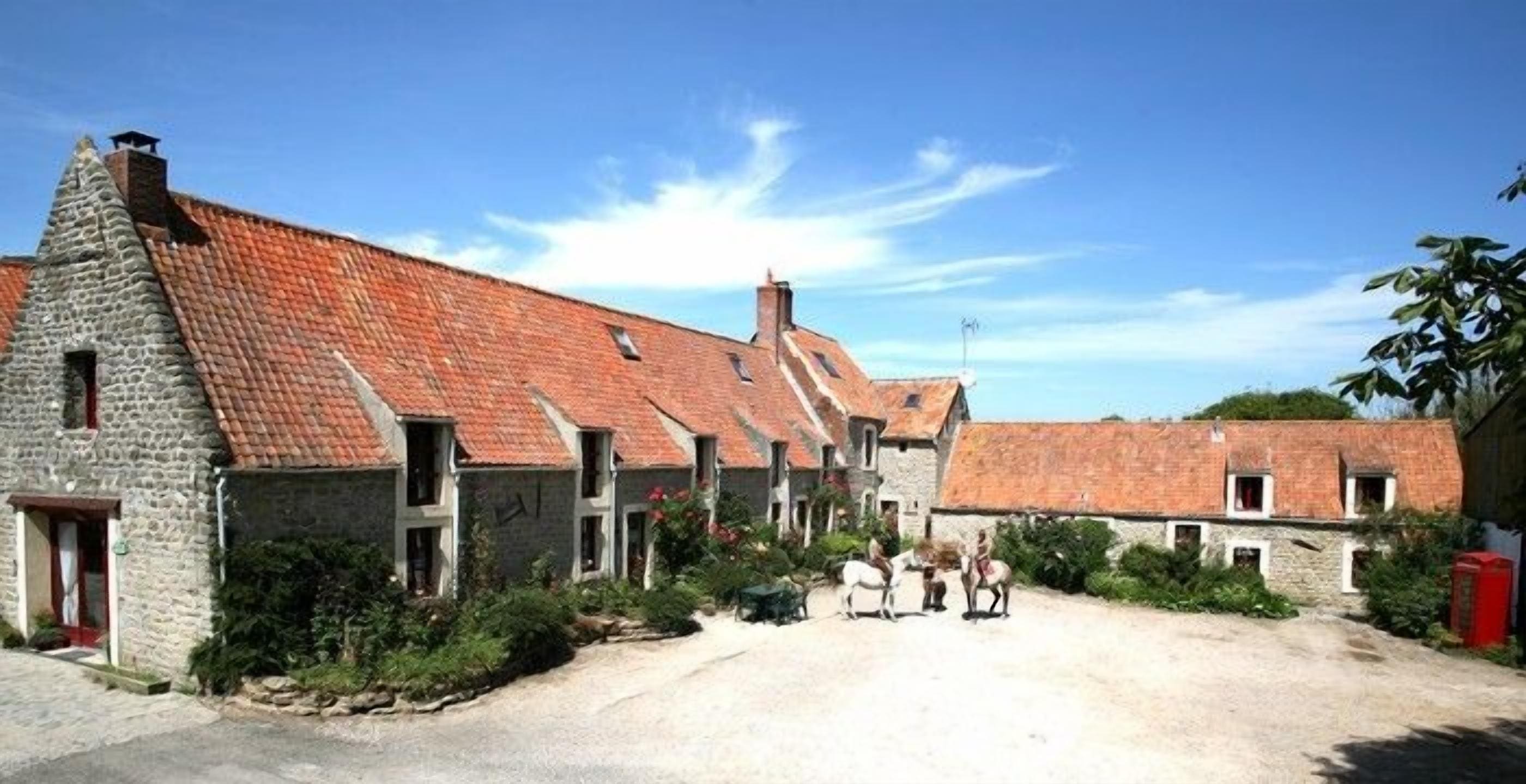 Ein traditionelles Steinhaus mit geneigtem Dach und einer Schotterzufahrt, im Vordergrund eine kleine Gruppe Personen.