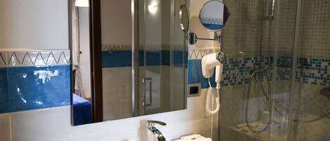 A bathroom with a white sink, a mirror, a handheld showerhead, and a glass-enclosed shower.