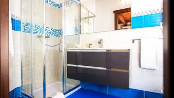 Een moderne badkamer met een douche in een glazen cabine, een zwart wastafelmeubel en een vloer betegeld met blauwe tegels.