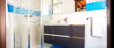 A modern bathroom with a glass-enclosed shower, a black vanity, and a blue-tiled floor.