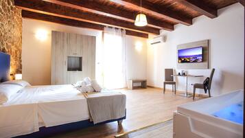 A hotel room with a wooden ceiling, a bed with white linens, a small desk, a chair, and a TV mounted on the wall.