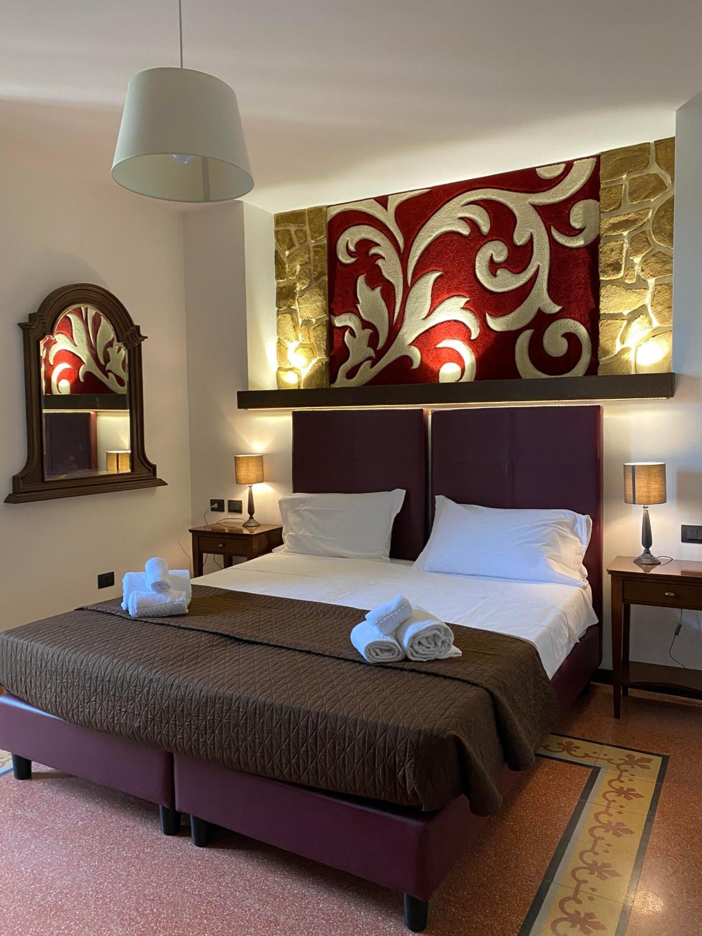 Une chambre d’hôtel avec un grand lit, deux tables de chevet, un miroir et un panneau décoratif mural.