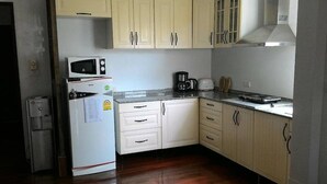 A compact kitchen with white cabinets, a microwave, a coffee maker, and a refrigerator. - Hua Hin Home (Hua Hin)