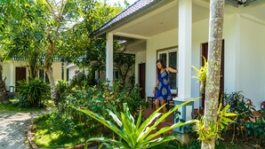 A woman in a blue dress standing at the entrance of a house with a garden. - Long Mountain Be Home 5 Resort (Phu Quoc)