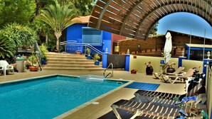 A swimming pool with steps leading up to a covered area, lounge chairs, and potted plants. - Ayelet Ahavim Hotel (Merom HaGalil)