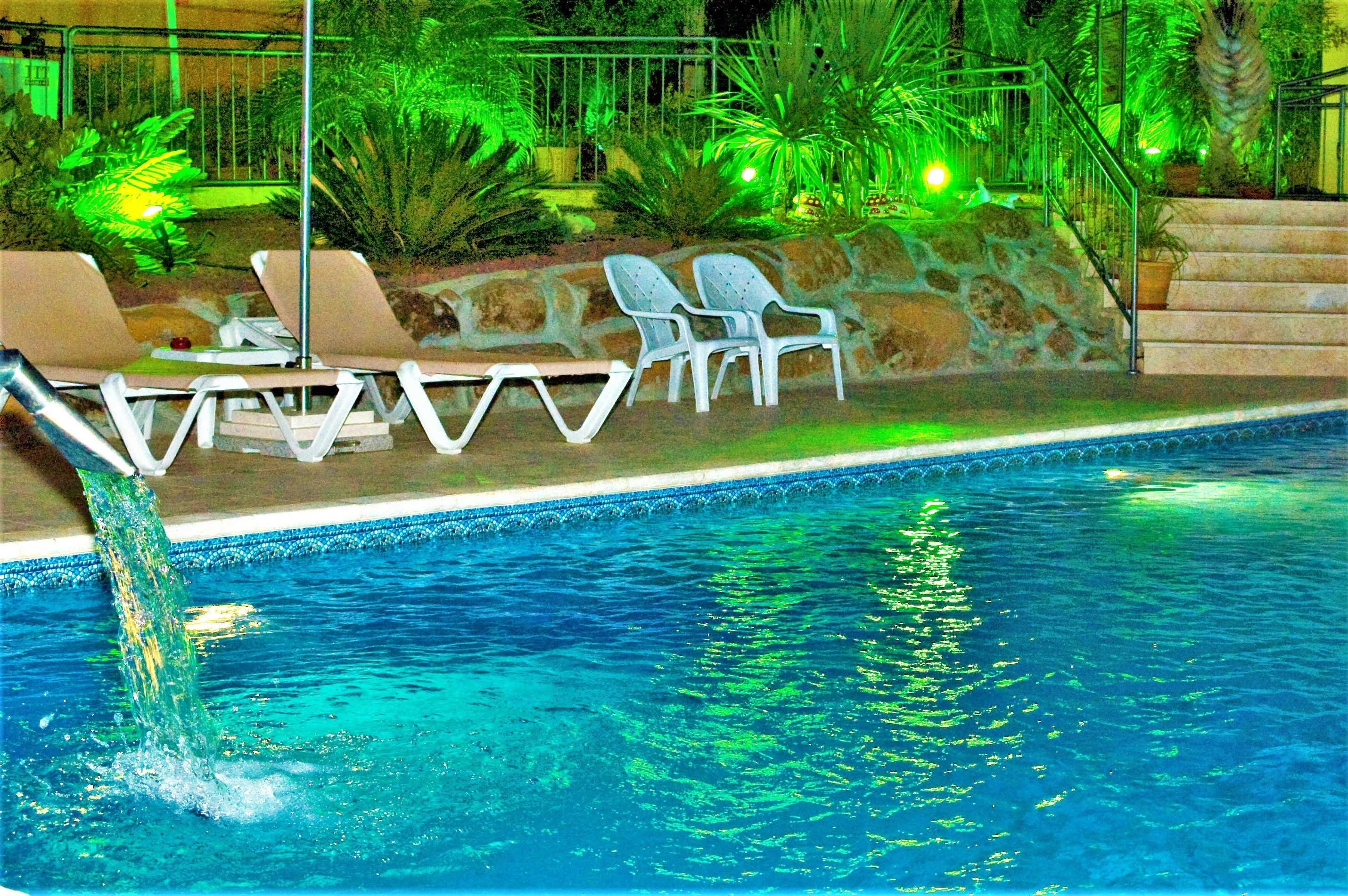 A swimming pool with lounge chairs and a stone wall.