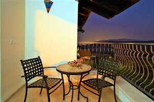 Un balcón con una mesa redonda y sillas, un cuenco decorativo y vistas del paisaje.