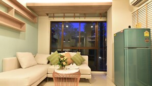 A modern living room with a sofa, a round coffee table, and a refrigerator. - Lumpini Park Beach Cha-Am Seaview A01-207 (Cha-am)