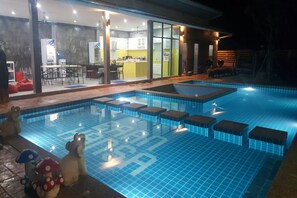 Une piscine dotée d’une terrasse carrelée et d’un patio fermé par des parois de verre.