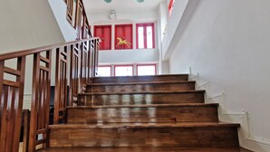 A wooden staircase with a handrail, leading to a landing with red doors and a yellow decorative element. - Lertnimit Boutique Hotel (Hua Hin)