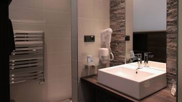 Un baño moderno con un espejo grande, un lavabo blanco y un perchero para toallas.