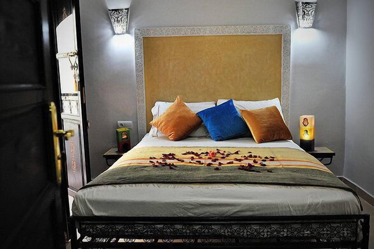 A neatly made bed with a patterned headboard, two bedside lamps, and a bedside table with a candle.