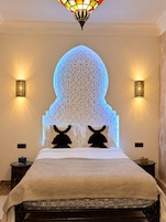 Un dormitorio con cama, apliques decorativos en la pared y una lámpara de techo original.