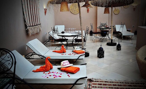 A clean, well-lit room with a round table and chairs, a small dining area, and a decorative wall hanging. - Dar Nossa (Marrakech)