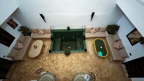 Une cour intérieure dotée d’une piscine centrale, d’espaces aménagés pour s’asseoir et d’éléments décoratifs.
