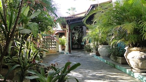 A courtyard with potted plants, a stone pathway, and a traditional archway. - Pousada Arco íris (Barra de Santo Antonio)