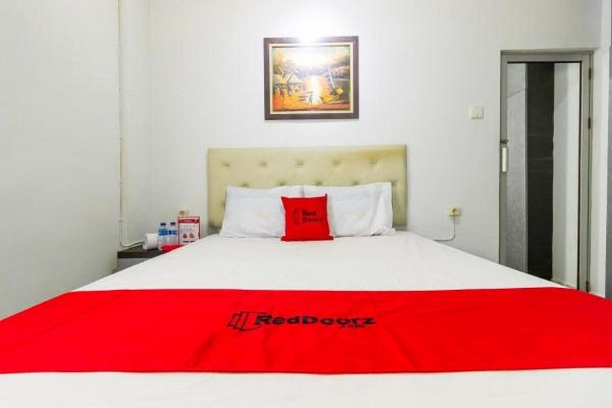 Una habitación de hotel con una cama, un cuadro en la pared y una puerta.
