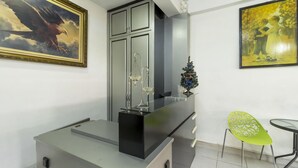 A modern kitchen with a black countertop, a glass-top dining table, and a green chair. - Reddoorz near Gajah Mada Plaza 2 (Jakarta)