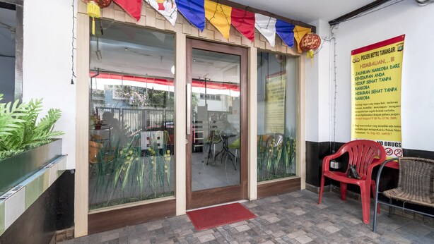 A building entrance with glass doors, a red mat, and a banner with text. - Reddoorz near Gajah Mada Plaza 2 (Jakarta)