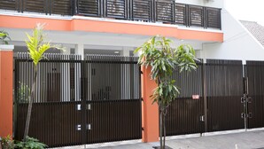 A gated residential area with a modern building, a balcony, and a tree in the foreground. - RedDoorz @ Pasir Luyu Buahbatu (Bandung)