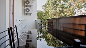 A balcony with air conditioning units, a drying rack, and a view of trees. - RedDoorz @ Pasir Luyu Buahbatu (Bandung)