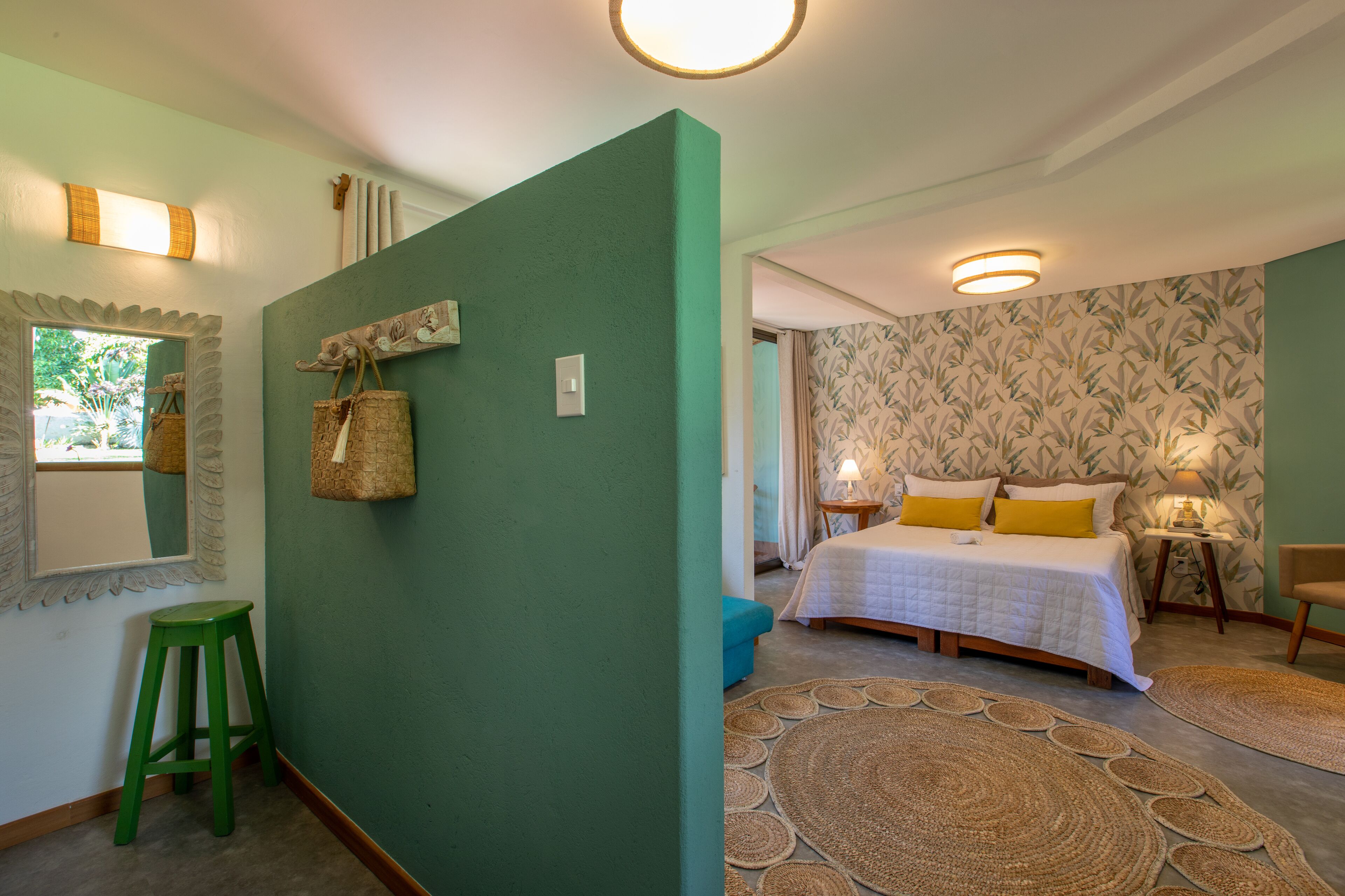Un dormitorio con cama, pared verde, ventana y un taburete verde.