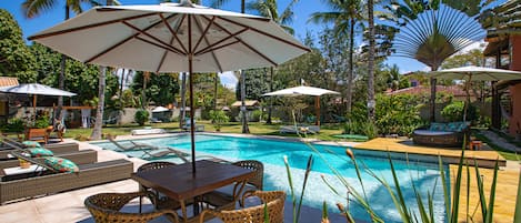 Una piscina al aire libre, sombrillas, sillones reclinables de piscina