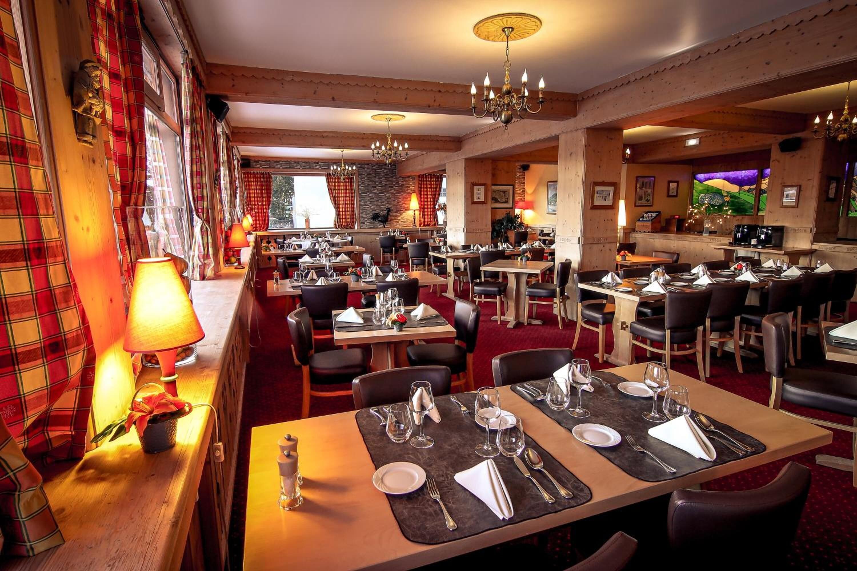 A restaurant with multiple dining tables, chairs, and chandeliers.