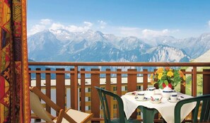 A balcony with a table set for tea, overlooking a mountainous landscape. - Hôtel Le Castillan (Huez)