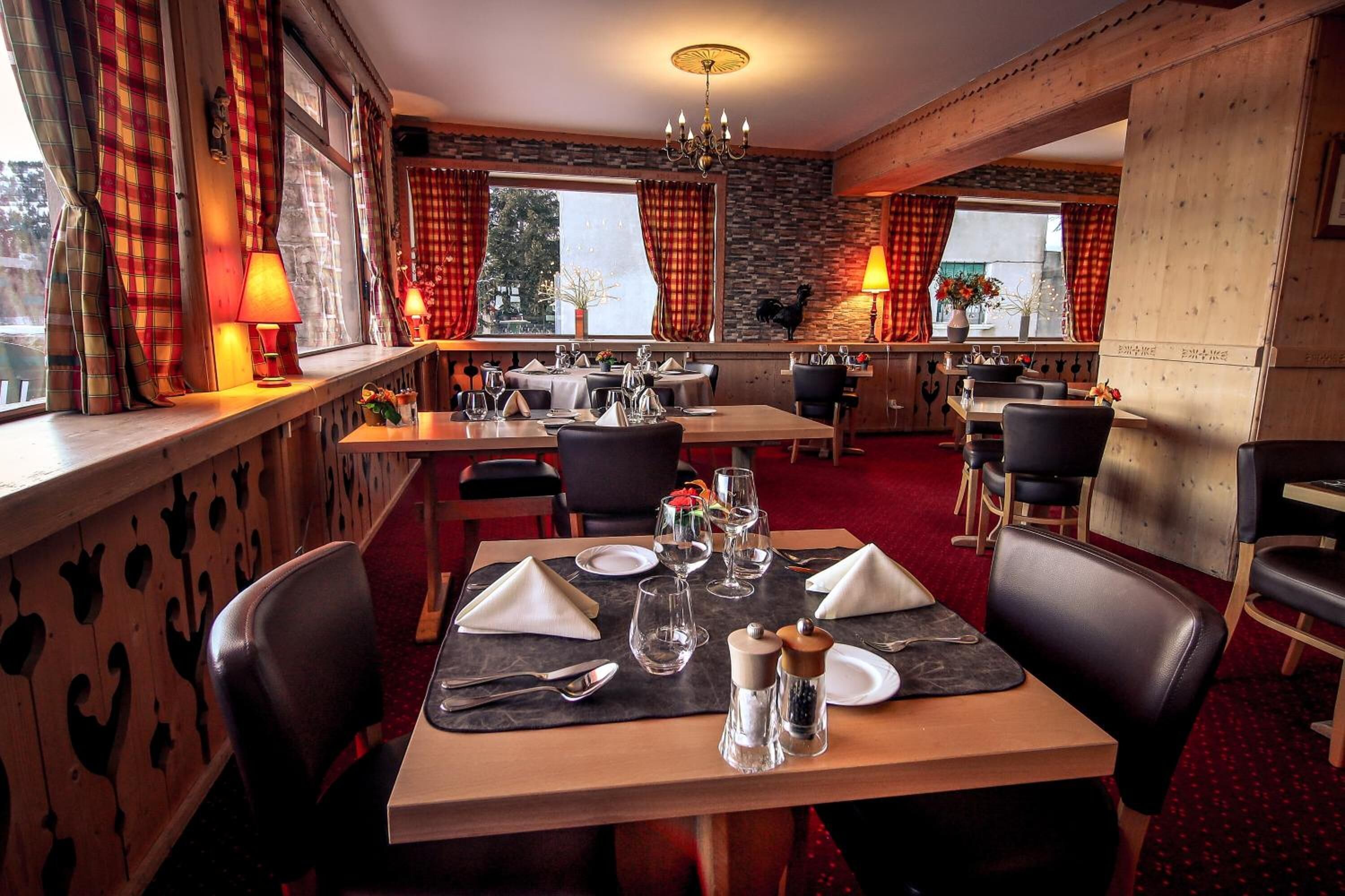 Ein Restaurant mit mehreren gedeckten Tischen, das ein rustikales Interieur mit freiliegenden Holzbalken und Steinwänden aufweist.