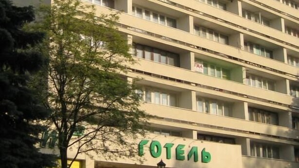 A multi-story hotel with a modern architectural design, featuring a prominent entrance with a green sign. - Tourist Hotel (Lviv)