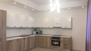 A modern kitchen with white cabinets, a built-in microwave, a coffee maker, and a dishwasher.