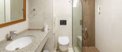 A bathroom with a granite countertop sink, a toilet, and a glass-enclosed shower.