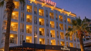 A multi-story hotel with balconies, a covered entrance area, and palm trees. - Kayhanbey Otel (Kuşadası)