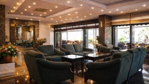 A spacious lobby with green upholstered seating, a central coffee table, and large windows offering views of the outdoors. - Kayhanbey Otel (Kuşadası)