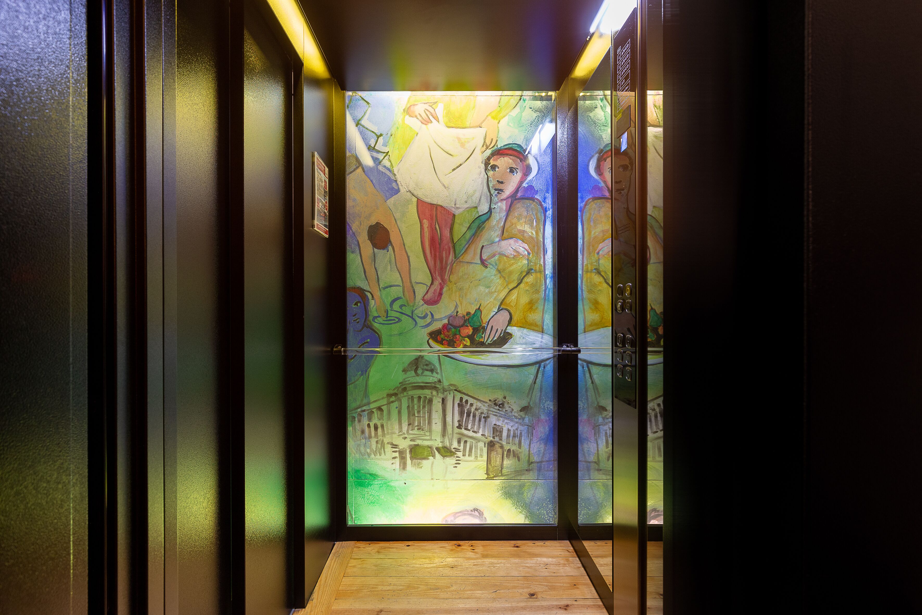 A narrow hallway with a mural on the walls depicting a figure in a white robe and another figure in a yellow robe.