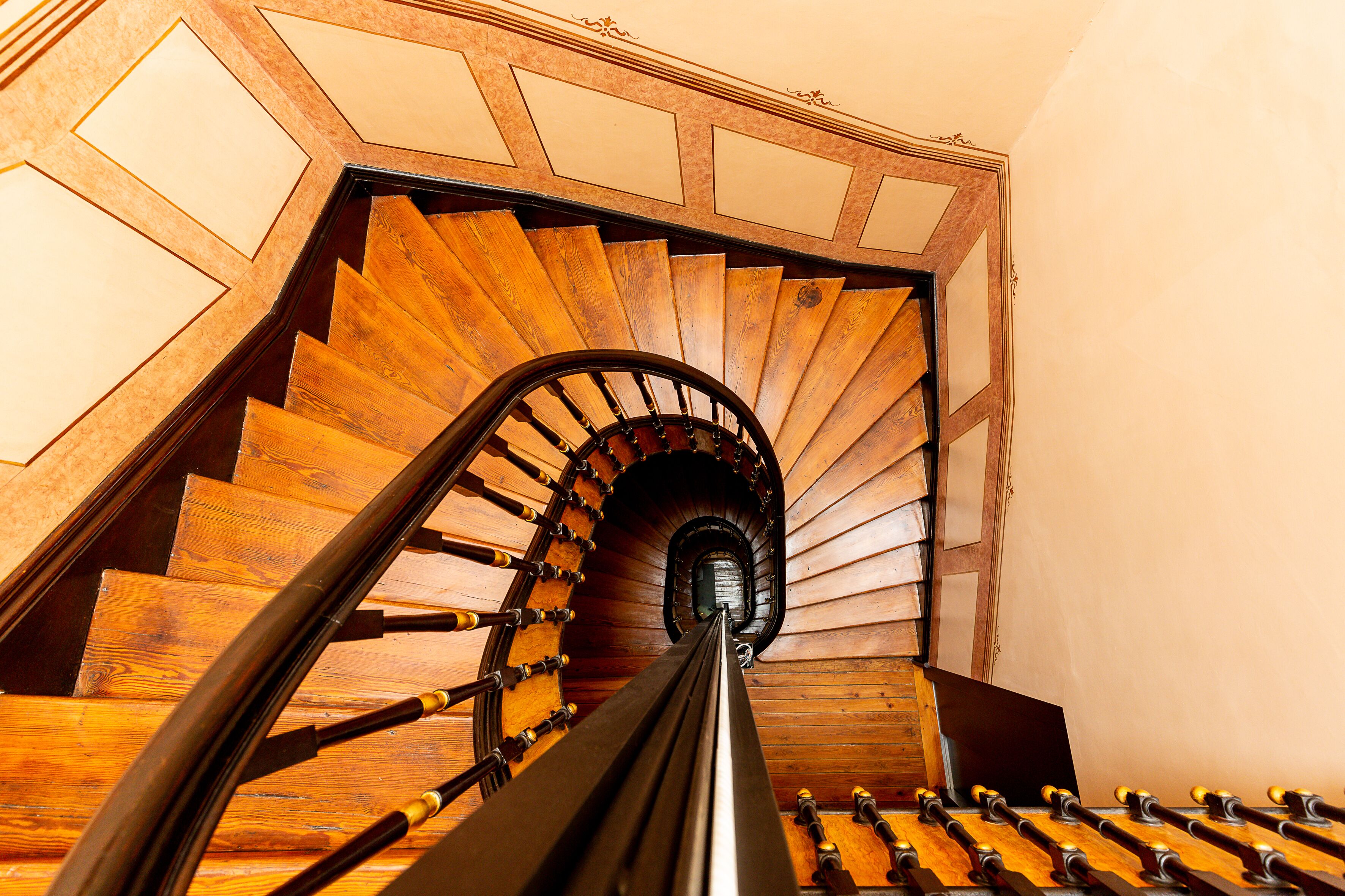 A wooden spiral staircase with a handrail and a series of steps leading upwards.
