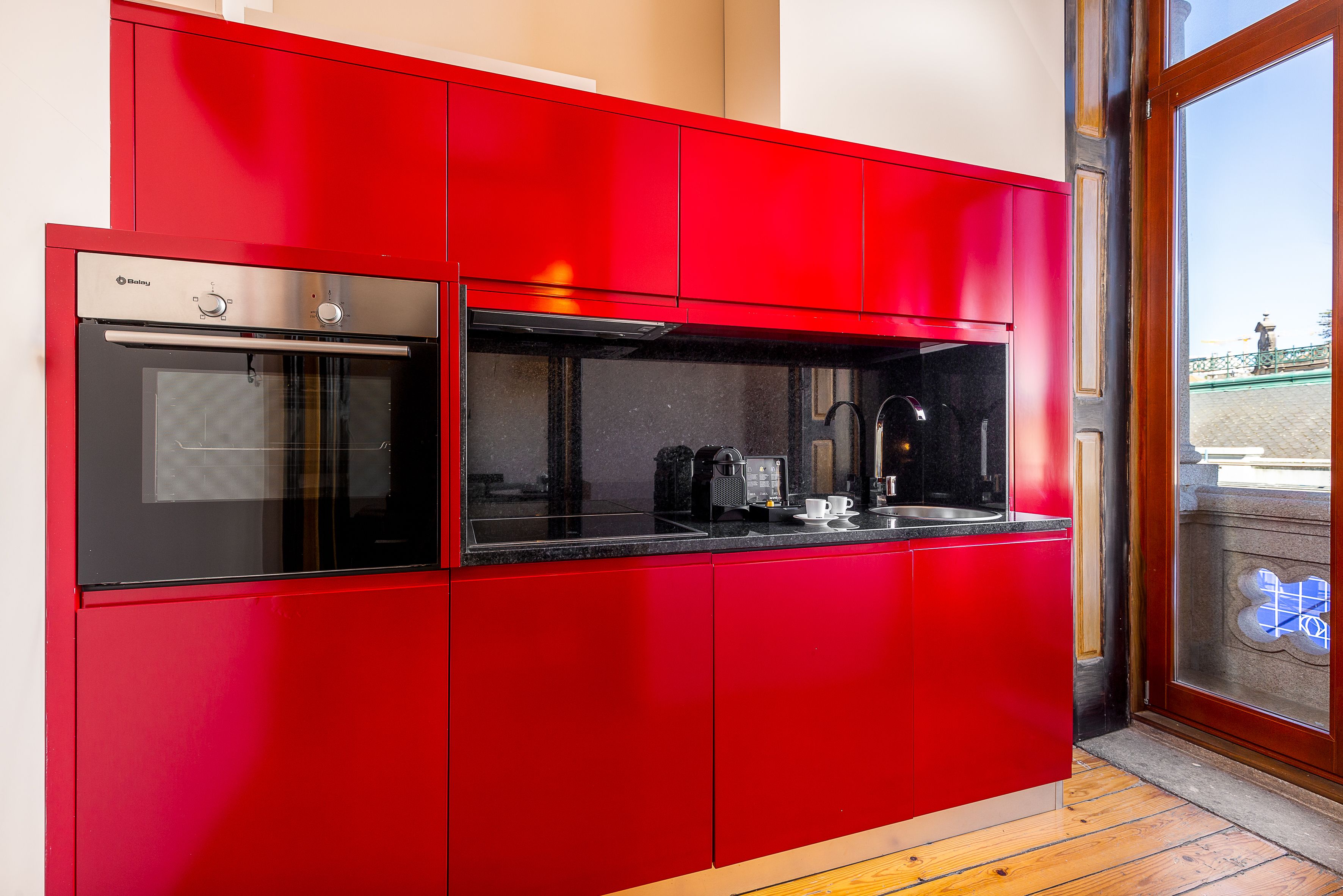 A modern kitchen with red cabinetry and a built-in oven.