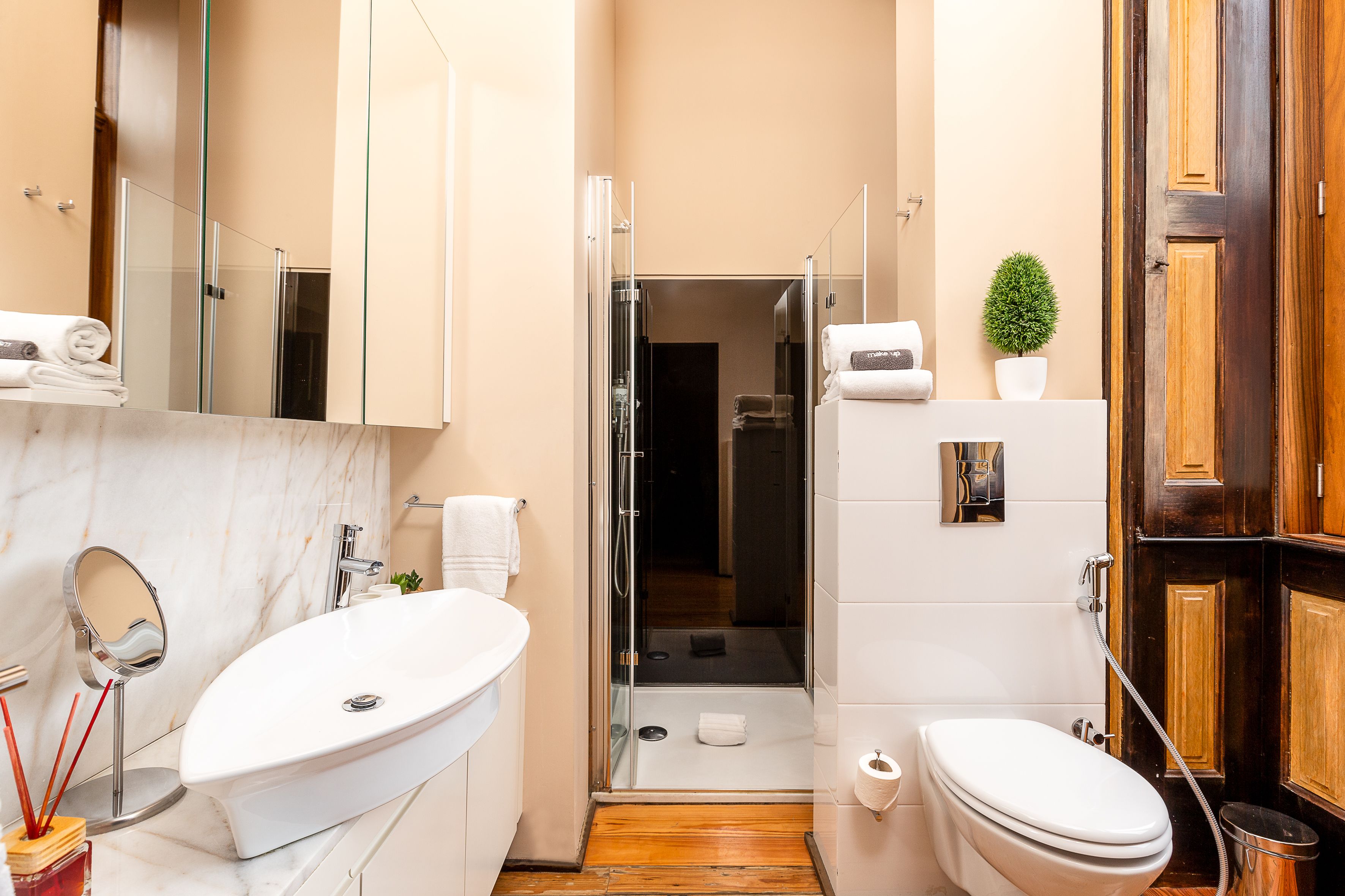 A compact bathroom with a white sink, a toilet, and a glass-enclosed shower.