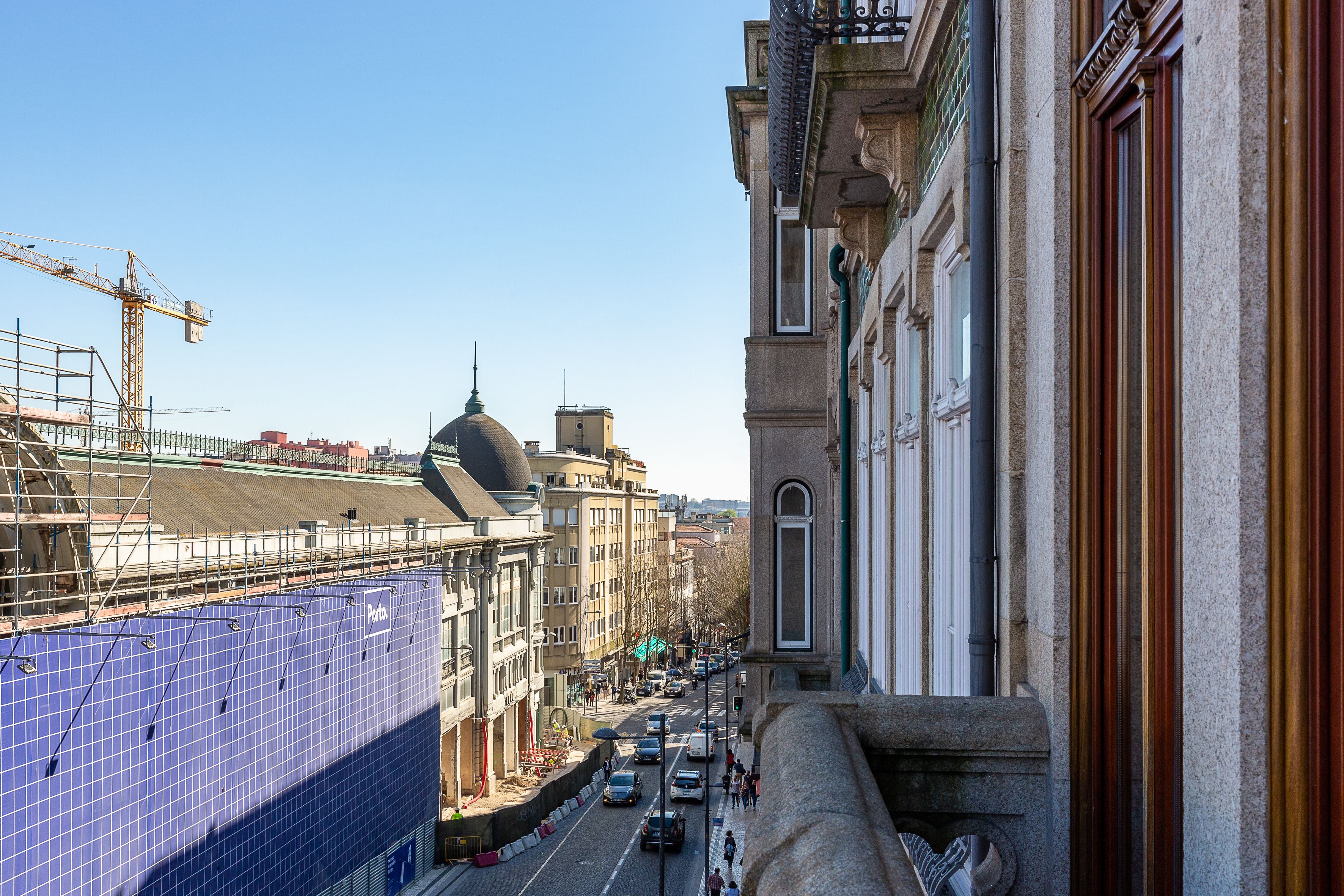 Une vue de rue avec un bâtiment doté d’une grande façade bleue, d’un dôme et d’une grue de construction en arrière-plan.