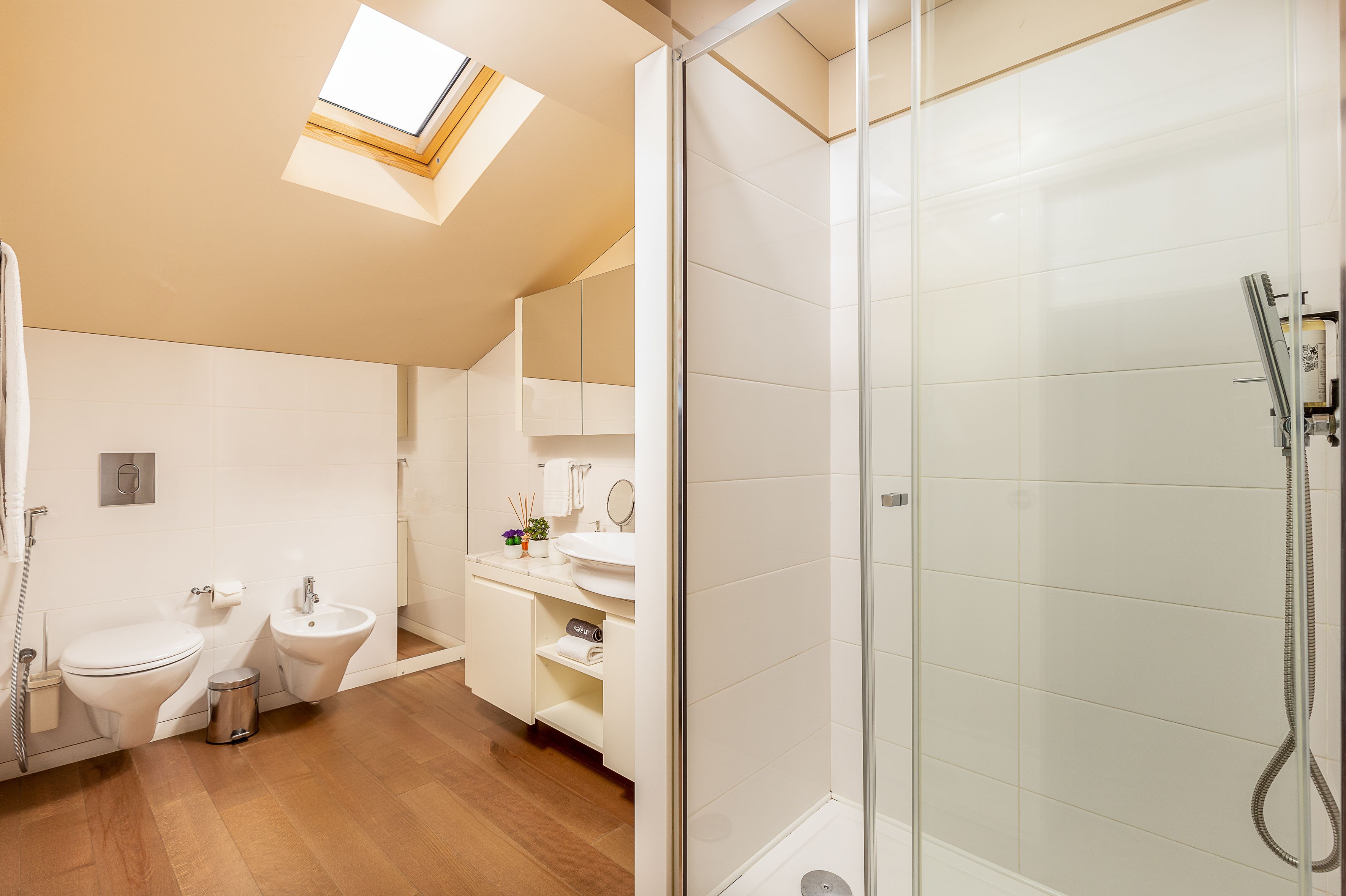 Un baño moderno con tragaluz, ducha, inodoro y bidé.