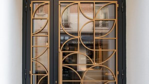A black door with a geometric pattern and a gold logo above it. - Hôtel de l'Espérance (Paris)