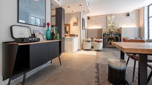 A modern kitchen with a black countertop, white cabinets, and a wooden dining table. There are stools and a rug on the floor. - Hôtel de l'Espérance (Paris)