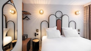 A modern hotel room with a large bed, a round mirror, and two wall-mounted light fixtures. - Hôtel de l'Espérance (Paris)