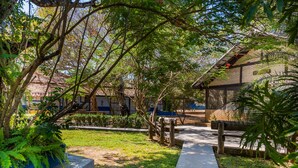 A pathway leading to a building with a brick facade, surrounded by greenery and trees. - Pousada Rio Claro (Pocone)